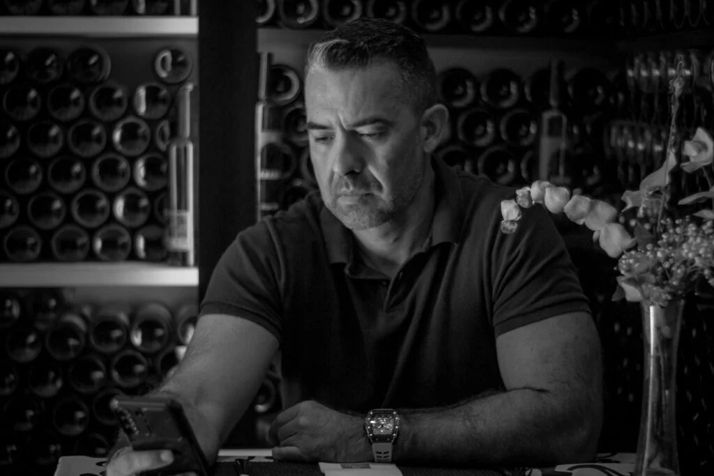 Juan Miguel, gerente de Paraleldrinks, en la oficina con las estanterías de botellas al fondo